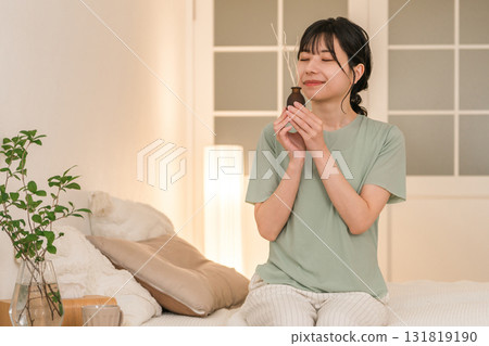 Young Asian woman smelling room fragrance in her bedroom 131819190