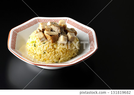 Egg fried rice topped with diced pork slices photographed against a black background 131819682