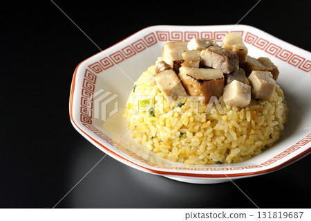 Egg fried rice topped with diced pork slices photographed against a black background 131819687