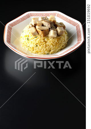 Egg fried rice topped with diced pork slices photographed against a black background 131819692