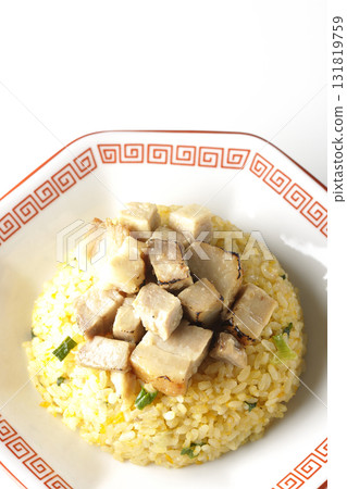Egg fried rice topped with diced pork slices photographed against a white background 131819759