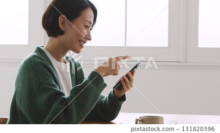 A woman in her 40s smiling and looking at her mobile phone screen A woman in her 40s smiling and looking at her mobile phone screen 131820396