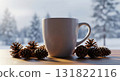 Warm White Mug Surrounded by Pinecones on a Wooden Table With a Snowy Winter Scene 131822116