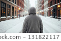 Person in Hooded Sweater Walking on Snowy Street Between Buildings During Winter 131822117