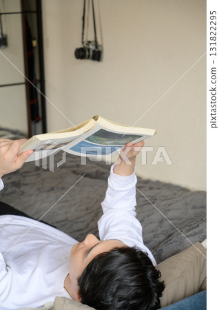A Japanese man lying on his back reading a book A Japanese man lying on his back reading a book 131822295