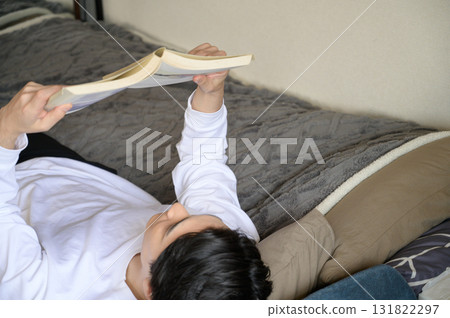 A Japanese man lying on his back reading a book A Japanese man lying on his back reading a book 131822297