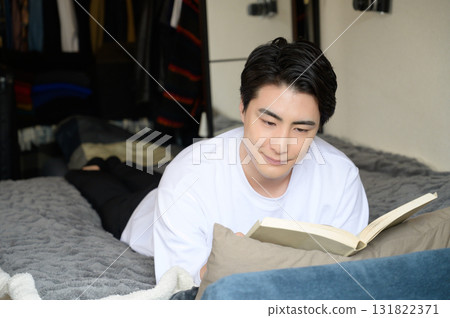 一名男子趴在床上看書 131822371