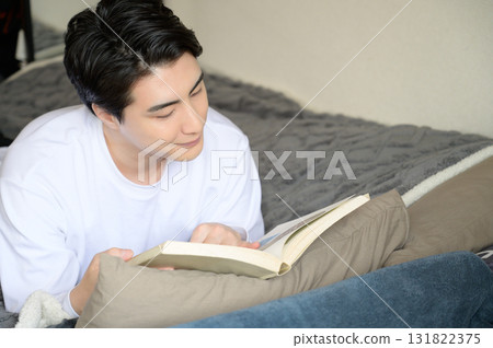 一名男子趴在床上看書 一名男子趴在床上看書 131822375