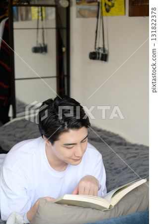 一名男子趴在床上看書 131822378