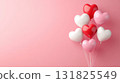 Colorful heart-shaped balloons gathered together against a pink background for a festive celebration 131825549