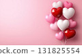 Colorful heart-shaped balloons arranged against a soft pink background for a festive celebration 131825554