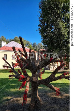 Woven straw ritual tree adorned with red ribbons in a sunny courtyard 131827472
