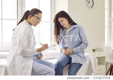 Young woman suffering from stomach ache having consultation with doctor in medical offic Young woman suffering from stomach ache having consultation with doctor in medical offic 131827559