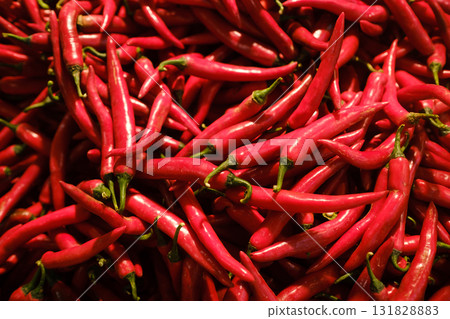 Bright red chili peppers stacked in a market setting during early morning hours, showcasing fresh produce for culinary uses and local dishes Bright red chili peppers stacked in a market setting during early morning hours, showcasing fresh produce for culinary uses and local dishes 131828883