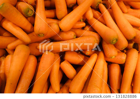 Fresh, vibrant carrots stacked in a market in bright orange hues ready for sale and cooking Fresh, vibrant carrots stacked in a market in bright orange hues ready for sale and cooking 131828886