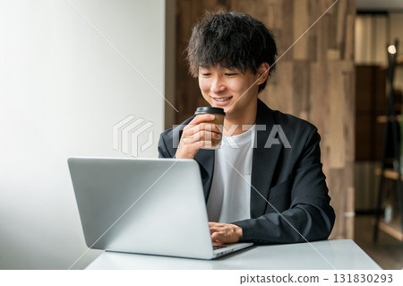 A businessman/man working on a computer in a cafe/shared office A businessman/man working on a computer in a cafe/shared office 131830293