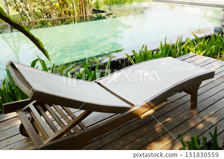 Sun loungers on the wooden deck with pool in tropical garden of resort in Asian 131830559