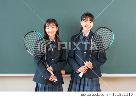 A middle school girl student holding a tennis racket in front of a blackboard in a school classroom 131831110