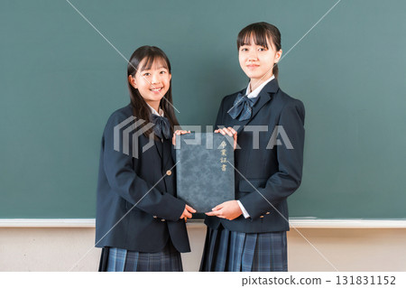 High school student/girl holding a diploma in front of a blackboard in the classroom (graduate/graduation ceremony/graduation) 131831152