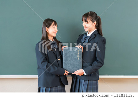 High school student/girl holding a diploma in front of a blackboard in the classroom (graduate/graduation ceremony/graduation) High school student/girl holding a diploma in front of a blackboard in the classroom (graduate/graduation ceremony/graduation) 131831153