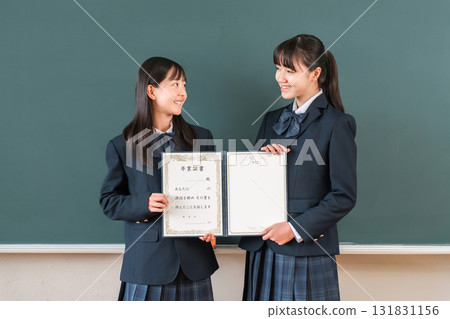 High school student/girl holding a diploma in front of a blackboard in the classroom (graduate/graduation ceremony/graduation) 131831156
