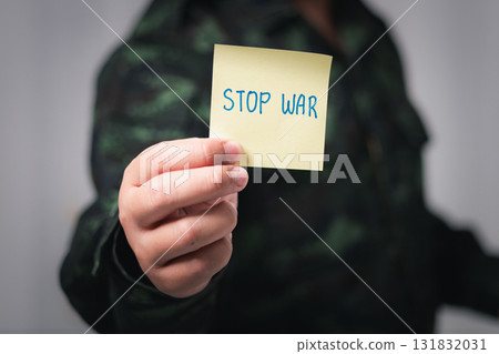 Protest for peace activist holds stop war sign urban setting somber atmosphere close-up anti-war message Protest for peace activist holds stop war sign urban setting somber atmosphere close-up anti-war message 131832031