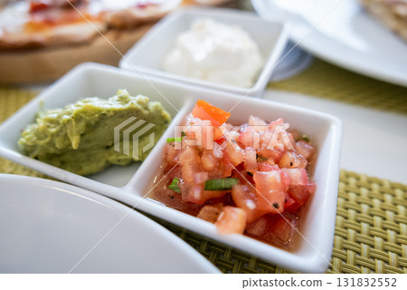 Fresh guacamole and salsa platter local restaurant food vibrant setting close-up culinary experience Fresh guacamole and salsa platter local restaurant food vibrant setting close-up culinary experience 131832552