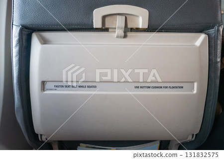 Safety instructions displayed airplane tray table during flight interior view travel environment Safety instructions displayed airplane tray table during flight interior view travel environment 131832575