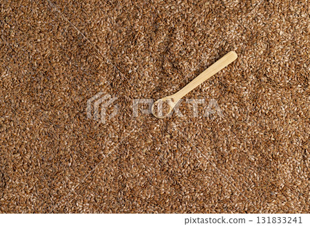 flax for sowing in a wooden spoon, a large number of light brown flax seeds and a spoon with seeds 131833241