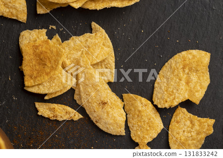 potato chips fried in oil and sprinkled with spices of dried red sweet pepper, a large number of salty pepper-flavored chips with aromatic spices 131833242