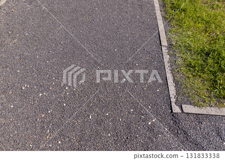 a narrow walking path in the park made of finely crushed rubble, not a wide path for pedestrians to walk in the park in sunny weather 131833338