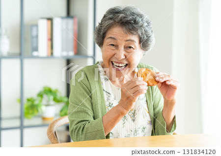 Senior woman eating rice crackers 131834120