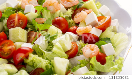 A vegetable salad with shrimp in the foreground. A nutritious dish featuring vibrant vegetables, feta cheese, and shrimp. 131835081