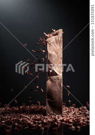 Large piece of dark chocolate and falling chocolate crumbs. Large piece of dark chocolate and falling chocolate crumbs. 131835891