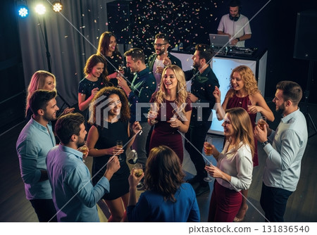 A group of friends celebrate together, toasting with champagne glasses amid falling confetti at a lively party, while a DJ plays music nearby A group of friends celebrate together, toasting with champagne glasses amid falling confetti at a lively party, while a DJ plays music nearby 131836540