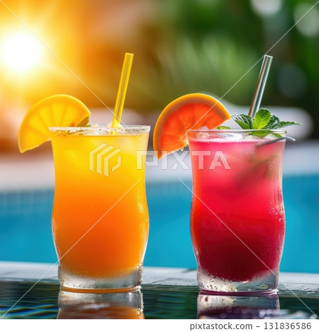 Two refreshing summer cocktails, one orange and one red, garnished with fruit slices and mint, stand by a swimming pool at sunset Two refreshing summer cocktails, one orange and one red, garnished with fruit slices and mint, stand by a swimming pool at sunset 131836586