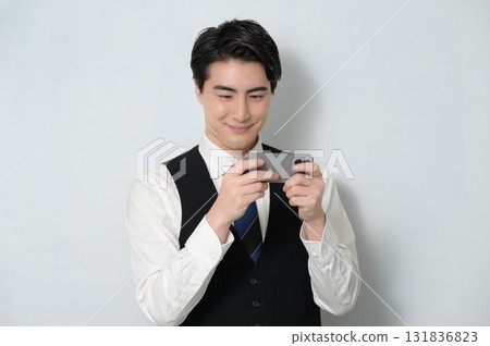 A man wearing a vest looking at his smartphone 131836823