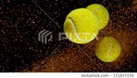 Freeze motion shot of a yellow tennis balls flying through the air, followed by a dynamic trail of clay dust. Freeze motion shot of a yellow tennis balls flying through the air, followed by a dynamic trail of clay dust. 131837226