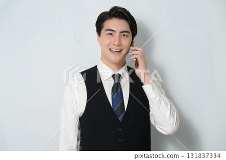 A man wearing a vest talking on a smartphone 131837334