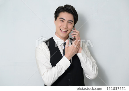 A man wearing a vest talking on a smartphone 131837351