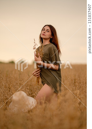 Woman holding wheat while standing in an oat field at sunset Woman holding wheat while standing in an oat field at sunset 131837407
