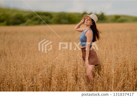 Model poses in a golden field of oats and wheat on a sunny day 131837417