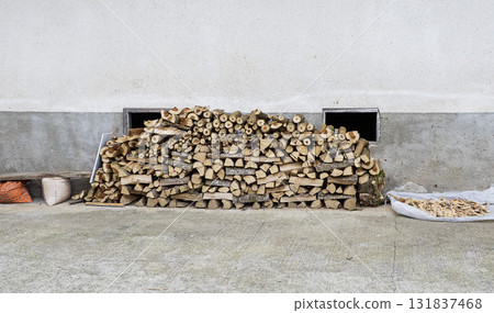 A pile of firewood, consisting of various sizes and shapes of wood pieces, is stacked in an outdoor scene. A pile of firewood, consisting of various sizes and shapes of wood pieces, is stacked in an outdoor scene. 131837468