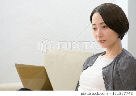 Woman sitting on sofa and working on computer 131837748