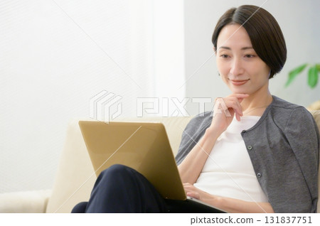 Woman sitting on sofa and working on computer 131837751
