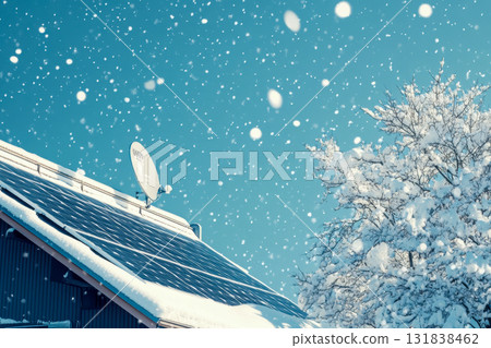 Snowflakes gently fall over solar panels installed on a house roof under a bright blue sky, showcasing winter beauty 131838462