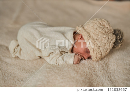 Full body top-down view of a newborn baby peacefully sleeping with a pacifier in a neutral cable 131838667