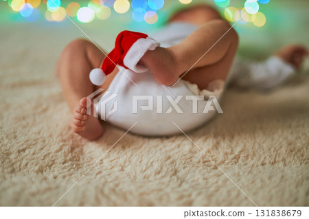 Close-up shot of a newborn baby lying on its back with its tiny feet in the air, one of which has a 131838679