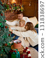 A happy family mother, father, and young son sitting close together in a cozy, festive living room 131838697