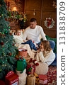 A happy family mother, father, and young son sitting close together in a cozy, festive living room 131838709